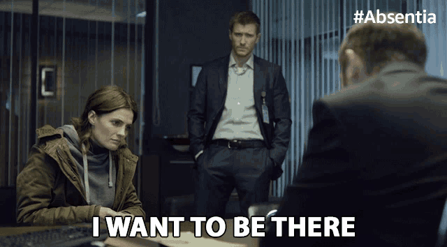 a man in a suit stands next to a woman sitting at a desk and says " i want to be there "