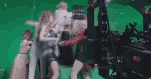 a group of women are standing in front of a green screen .
