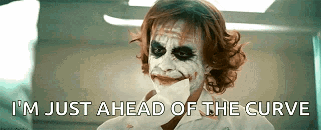 the joker is holding a piece of paper in his mouth and says i 'm just ahead of the curve