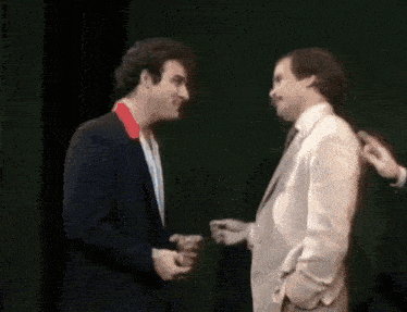 two men in suits are standing next to each other and talking