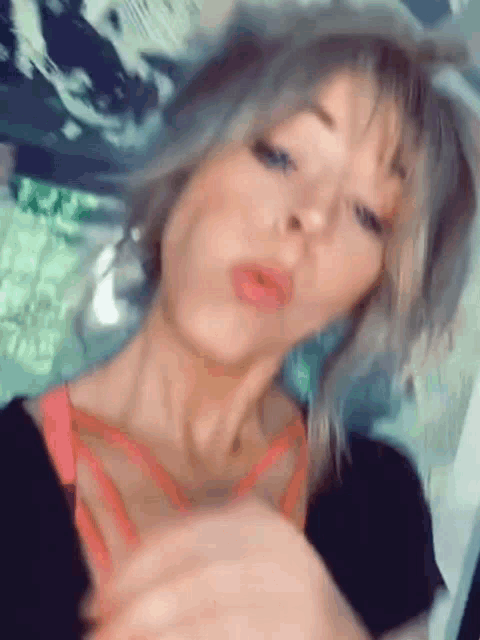 a close up of a woman making a funny face while wearing a black shirt and a pink bra .