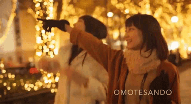 two women are standing in front of a christmas tree with the word omotesando on the bottom