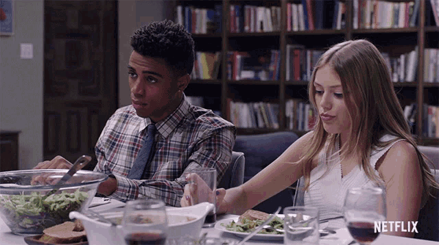 a man and a woman are sitting at a table with a netflix logo on the bottom