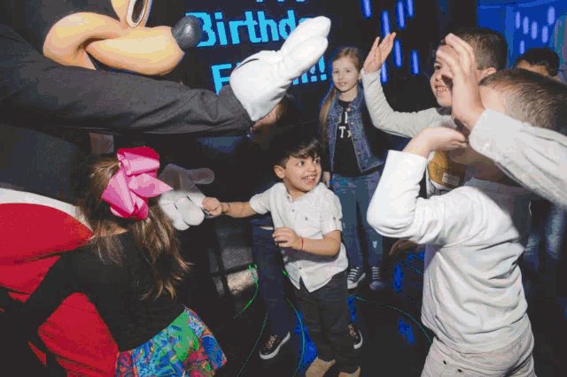 a group of children are dancing in front of a sign that says birthd