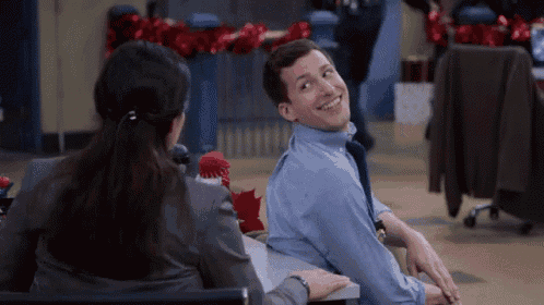 a man and a woman are sitting at a table talking to each other .