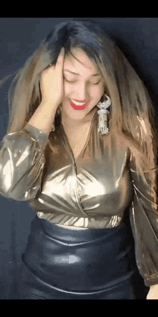 a woman wearing a gold top and a black leather skirt