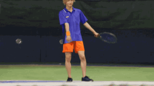 a man in a blue shirt is holding a tennis racquet