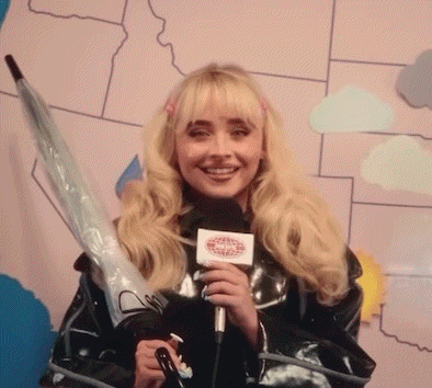 a woman is holding an umbrella and a microphone while being taped to a wall .