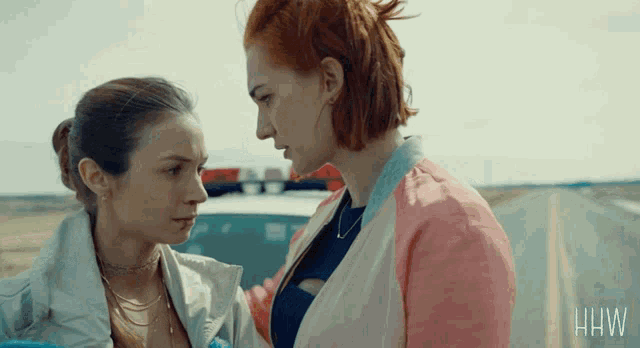 two women are standing next to each other on the side of a road with the letters hw on the bottom right