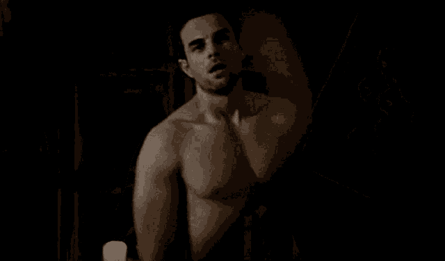 a shirtless man is standing in a dark room in front of a picture frame .
