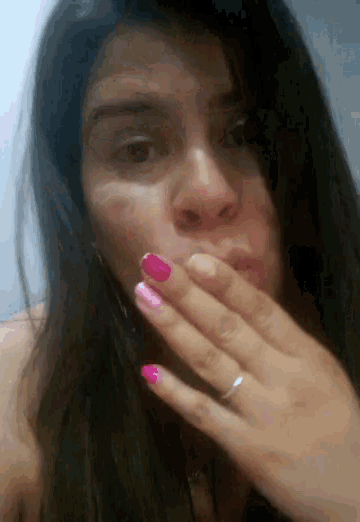 a woman covering her mouth with her hand and has pink nails