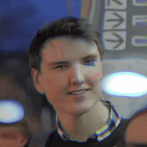 a young man is smiling in front of a sign that has arrows pointing up and down