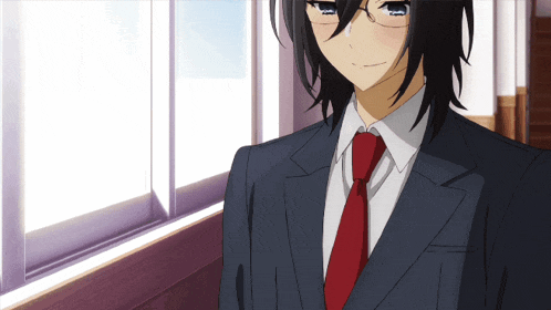 a man in a suit and red tie is standing in front of a window