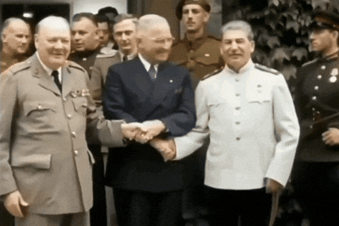 a group of men are shaking hands in front of a group of soldiers