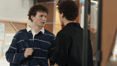 two young men are standing next to each other talking