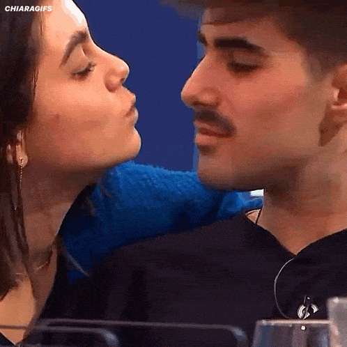 a man and a woman are kissing in front of a blue background with the words chiaragifs at the bottom