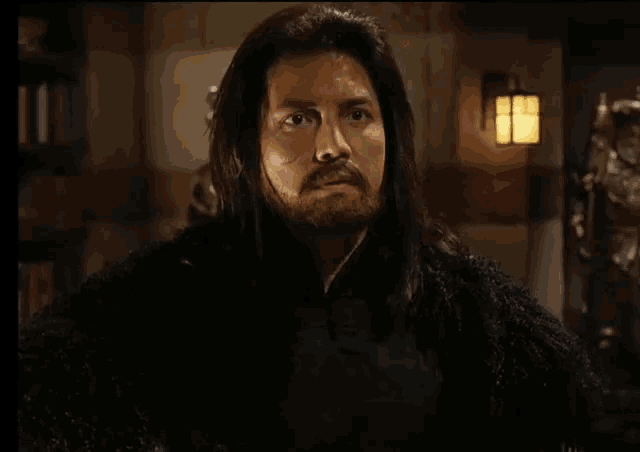 a man with long hair and a beard is wearing a fur coat