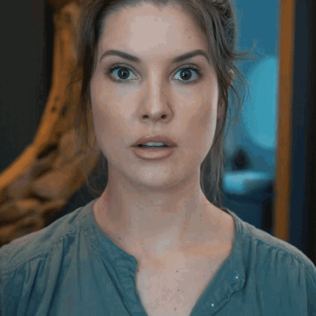 a woman with a surprised look on her face is wearing a blue shirt