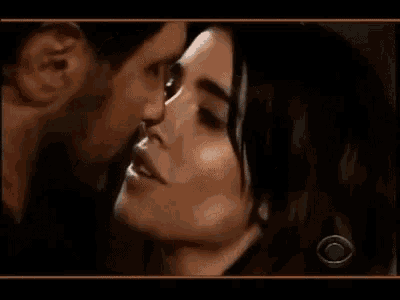 a man and a woman are kissing against a wall in a room .