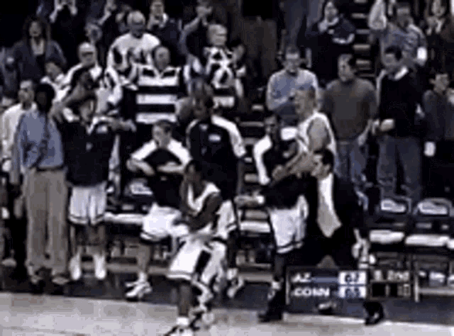 a group of basketball players standing on a court with a crowd watching .
