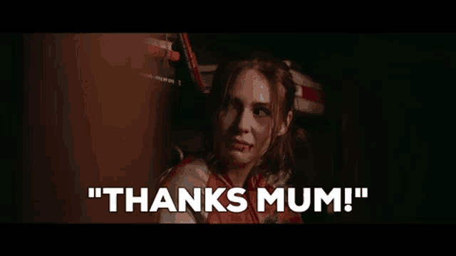 a woman with blood on her face is standing in a dark room and saying `` thanks mum '' .