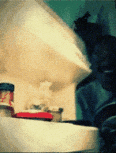 a blurred image of a person standing in front of a shelf with a jar of jam on it