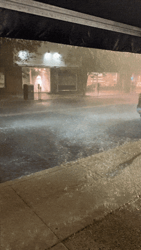 a car is driving down a rainy street in front of a store