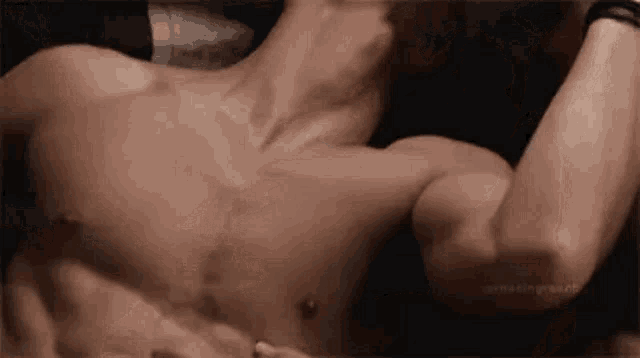 a shirtless man is laying on a bed with his arms outstretched .