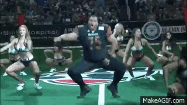 a man is dancing with cheerleaders on a field .