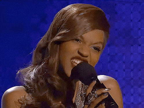 a woman singing into a microphone in front of a purple background