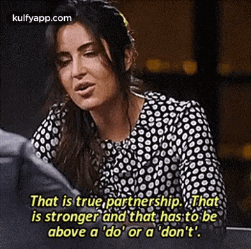a woman in a black and white polka dot shirt is sitting at a table with a quote .