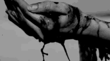 a black and white photo of a person 's bloody hand holding something .