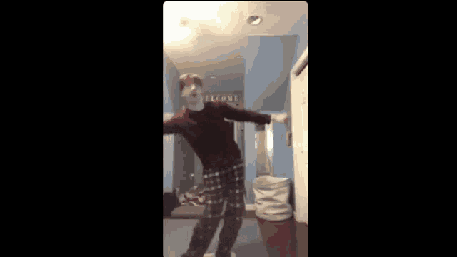 a man is dancing in a room with a welcome sign on the wall .