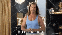 a man in a blue tank top is standing in front of a mirror and making a butter face gesture .