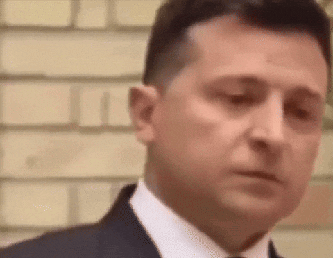 a man in a suit and tie is standing in front of a brick wall with his eyes closed .