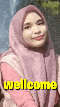 a woman wearing a pink hijab with the words wellcome written on it