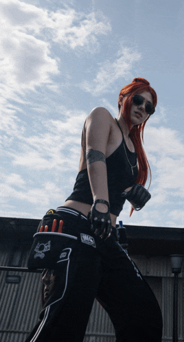 a woman with red hair is wearing a black top and black pants with the word mc on the side