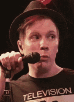 a man is singing into a microphone while wearing a television shirt .