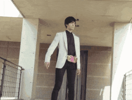 a man in a white jacket and black pants is standing in a hallway .