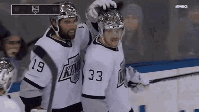 two hockey players wearing white jerseys with the number 33 on the back
