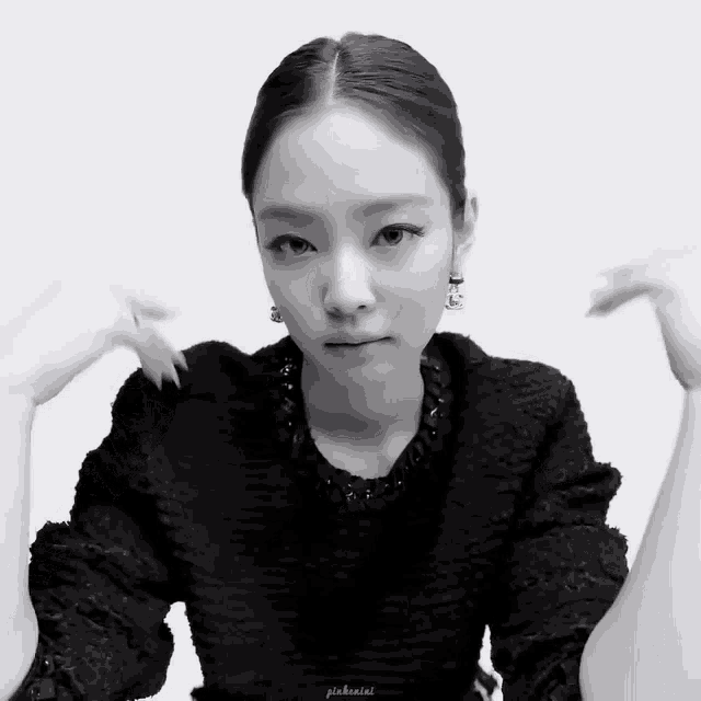 a black and white photo of a woman wearing a black sweater and earrings .