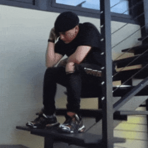 a man is sitting on a set of stairs with his head down
