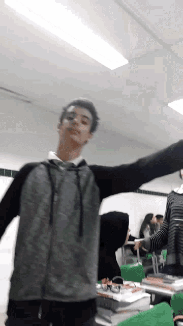 a boy with his arms outstretched stands in a classroom
