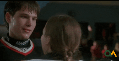 a man and a woman are kissing on a ice rink . the man is wearing a jersey that says ottawa