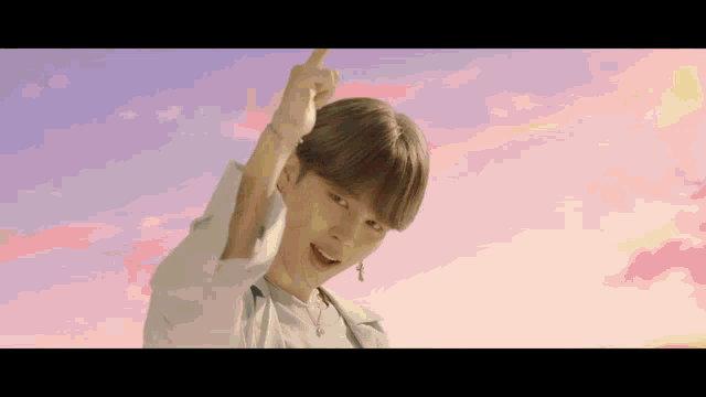 a young man is standing in front of a pink and purple sky .