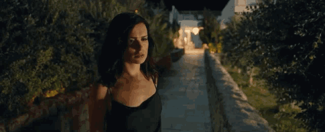 a woman in a black dress is standing in front of a building at night .