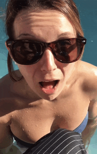 a woman wearing sunglasses is swimming in a pool with her mouth open