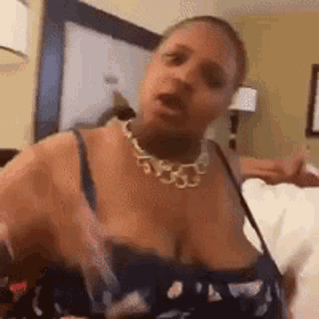 a woman with large breasts is sitting on a bed in a room .