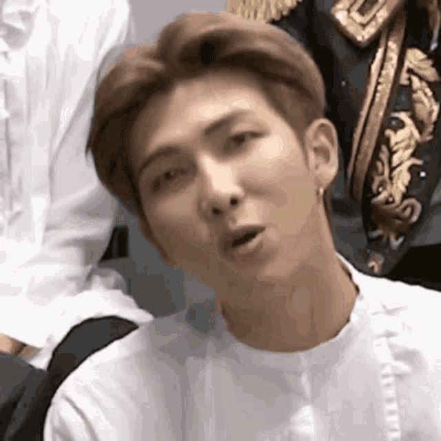 a close up of a person wearing a white shirt and earrings .