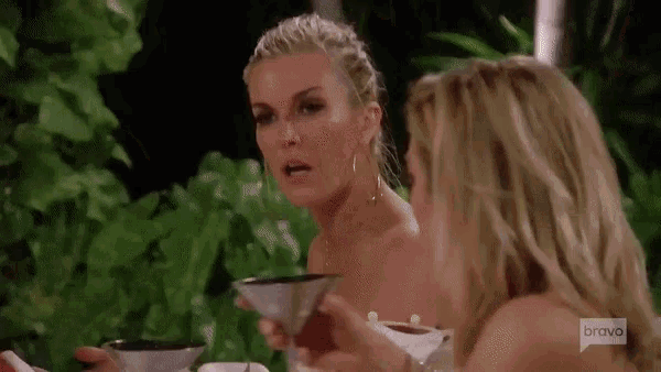 two women are sitting at a table with a martini in their hands .